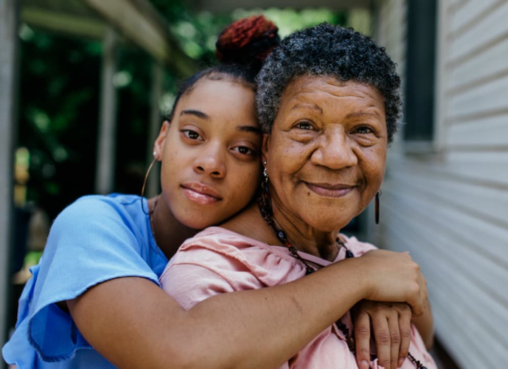 Grandmother and granddaughter smiling at camera