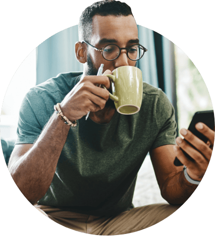 Man sipping coffee looking at computer screen