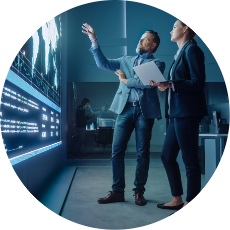 Man and woman have a discussion while looking at a large electronic display wall.