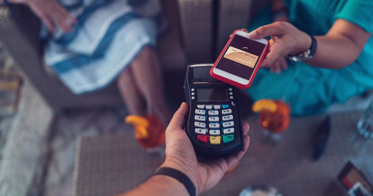 Customer paying bill on card machine using smartphone