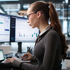 Woman wearing glasses working on a large computer monitor
