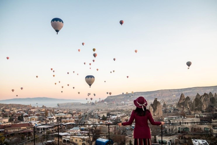 Woman watching hot air balloons on the horizon